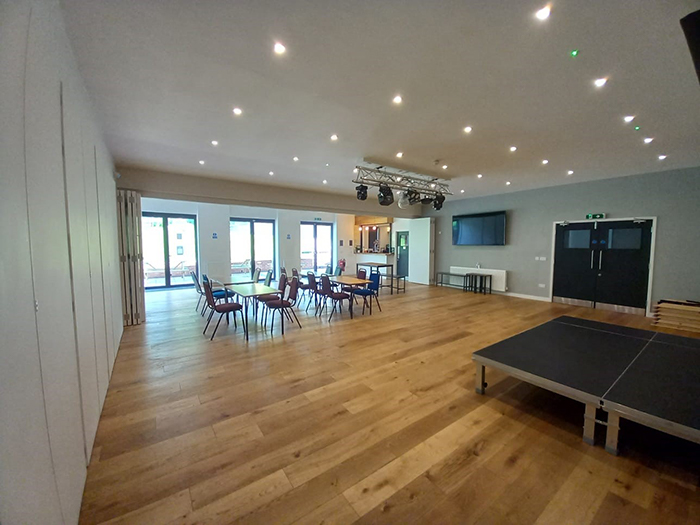View across the new community multi-function room towards the Milkchurn Café counter and French windows opening onto the terrace.